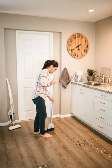 a-woman-in-a-green-shirt-and-black-gloves-vacuuming-a-gray-ottoman-5txz228u4eo